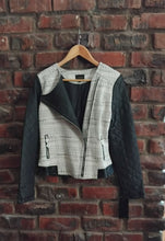 Load image into Gallery viewer, Black and cream jacket on a hanger against a brick wall