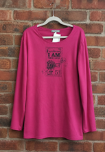 Load image into Gallery viewer, A bright pink long-sleeve t-shirt with a dark graphic print on the front, hanging on a hanger against a red brick wall background.