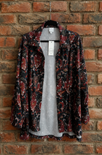 Load image into Gallery viewer, A long-sleeve open-front shirt jacket with a red, black, and blue paisley pattern, hanging on a brick wall.