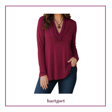 Load image into Gallery viewer, A woman wearing a long-sleeve burgundy top with a draped V-neckline, paired with dark blue jeans. The brand name 'hartgoet' is printed at the bottom of the image.