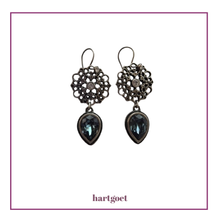 Load image into Gallery viewer, Pair of ornate earrings with dark blue Swarovski crystals on a light background, branded 'hartgoet'.