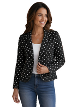 Load image into Gallery viewer, A woman modeling a black blazer with white polka dots, worn over a white top and blue jeans, against a plain white background.