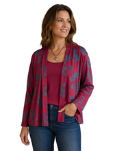 Load image into Gallery viewer, A woman wearing a burgundy open-front cardigan with a teal floral pattern over a solid burgundy top and blue jeans, standing against a white background.