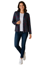 Load image into Gallery viewer, A woman modeling a navy blue cardigan with a red and teal geometric pattern, worn open over a white t-shirt and dark blue jeans, standing against a white background.
