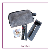 Load image into Gallery viewer, A gift set by hartgoet on a white background, enclosed in a purple border. The set includes a gray textured zippered pouch, a handheld massager, a pen-style gadget and scent for the car.