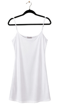 Load image into Gallery viewer, A white spaghetti-strap camisole top hanging on a black hanger against a white background.