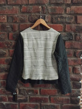 Load image into Gallery viewer, Black and cream patterned jacket on a hanger against a brick wall
