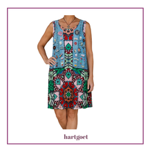 Load image into Gallery viewer, A sleeveless dress with a light blue denim-style top section covered in colorful patchwork details and a multicolor geometric and floral patterned skirt, shown on a model against a white background with a purple border. The brand name 'hartgoet' is printed at the bottom.
