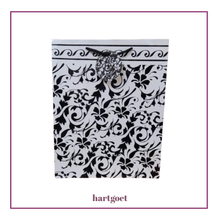Load image into Gallery viewer, Decorative gift bag with black floral pattern on a white background.  
