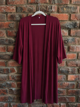 Load image into Gallery viewer, Maroon jacket on a hanger against a brick wall
