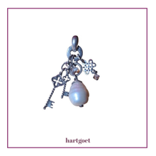 Load image into Gallery viewer, Silver charm with a key and pearl on a light pink background.  
