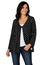 Load image into Gallery viewer, A woman modeling a black long-sleeve cardigan with white polka dots over a white top and blue jeans, with a white.
