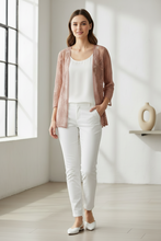Load image into Gallery viewer, A woman stands in a bright, minimalist room wearing a brown open-front cardigan over a white tank top and white pants, paired with white flats.
