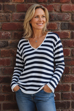 Load image into Gallery viewer, Model standing against a brick wall, wearing a white and navy jersey and jeans
