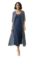 Load image into Gallery viewer, A woman models a navy blue slip dress with a matching open-front cardigan featuring a white and navy polka dot pattern. 
