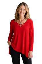 Load image into Gallery viewer, A woman wearing a bright red long-sleeve top with a criss-cross V-neckline detail, paired with black pants, standing against a white background.
