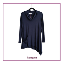 Load image into Gallery viewer, A dark navy blue long-sleeve cowl neck top with an asymmetrical draped hem and side pockets, hanging on a black hanger against a white background with a purple border and the brand name hartgoet below.
