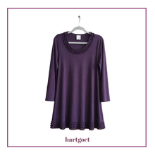 Load image into Gallery viewer, A purple long-sleeve tunic dress with a scalloped lace neckline and hem, hanging on a white hanger against a white background with a purple border. The brand name 'hartgoet' is printed below the dress.
