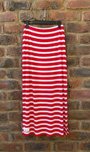 Load image into Gallery viewer, A red and white horizontally striped skirt hanging from a black hanger against a rustic red-brown brick wall.
