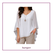 Load image into Gallery viewer, A woman wearing a white V-neck blouse with wide, draped sleeves and beige pants, shown against a white background with a purple border. The brand name 'hartgoet' is printed below.
